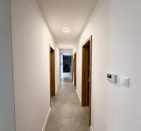 A hallway in a family house with a gray floor and white walls.