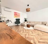 Living room with a large sofa, an armchair, and a wooden decor floor in a family house.