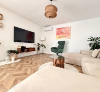 A spacious living room with a wooden-patterned floor and a comfortable corner sofa in a family house.