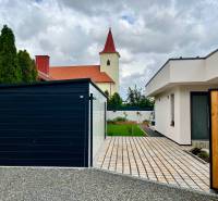 A family house in Trnava with a garden, garage, and a church in the background.