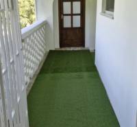 The balcony of a 2-room apartment with a green carpet and wooden doors.