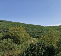 A wooded hill surrounded by greenery in the vicinity of the town Hollóháza, clear sky.