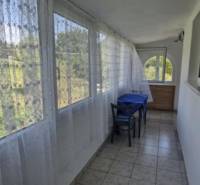 A glazed terrace in a 2-room apartment with a curtain and a view of nature.