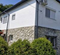 A stone house with a white facade surrounded by greenery in Hollóháza.