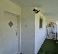 The entrance area of a 2-room apartment in Hollóháza with white doors and a green carpet.
