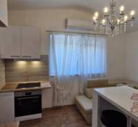 A kitchen in a 2-room apartment with a chandelier, a dining table, and a floor with a wooden design.