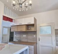 A kitchen in a 2-room apartment with a chandelier, wooden cabinets, and decorative elements.