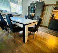 A kitchen in a 3-room apartment with a wooden decor floor and dark furniture.