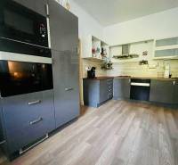 A kitchen in a 3-room apartment with a wooden decor floor and modern equipment.