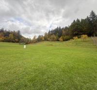 A woman in front of a construction plot in Zbora, Zbora Street, with contact information.