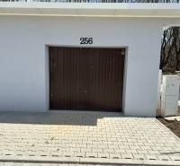 Garages in Liptovské Kľačany, simple design, white facade, brown gate, and paving.