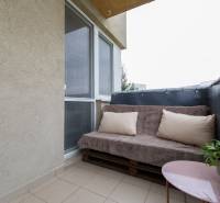 Balcony of a 2-room apartment with a sofa and a table on tiles.