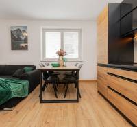 Living room with a sofa and a dining table in a 2-room apartment with wood-patterned flooring.