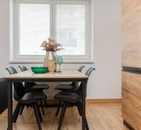 Dining table with black chairs in a two-room apartment with a wooden decor floor.