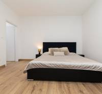 Bedroom in a 2-room apartment with a large bed and a floor with a wooden decor.