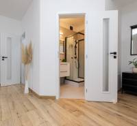 A hallway in a 2-room apartment with a wooden decor floor and an entrance to the bathroom.
