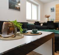 Stylish 2-room apartment with wood-patterned flooring, a comfortable sofa, and fern leaves.