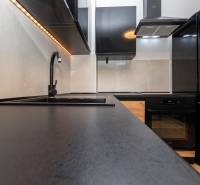 A stylish kitchen with black appliances and a wooden decor floor in a 2-room apartment.