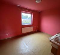 A room in a family house with red walls and simple furniture.