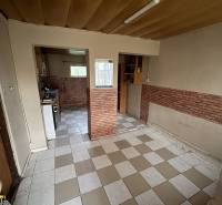 A kitchen and dining area in a family house with a tiled floor and brick cladding.