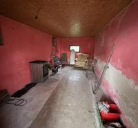 A room in a family house with red walls, a wooden decor ceiling, and simple furnishings.