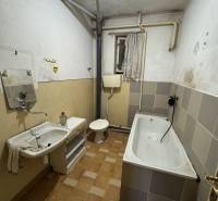 A bathroom in a family house with a bathtub and a sink, simple design with tiles.