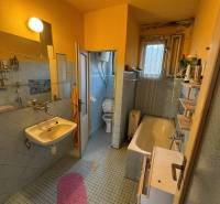 A bathroom in a family house with a bathtub, sink, and toilet in light tones.