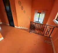 Orange walls and staircase in a family house with geometric patterns and a window.