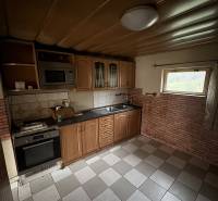 A kitchen in a family house with a kitchen unit, tiles, and appliances.