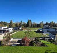 Residential plots in Kováčová with modern houses, landscaped gardens, and greenery.