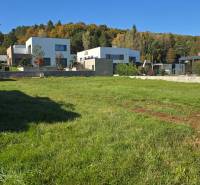 Plots - housing in Kováčová with modern houses and a forest environment in the background.