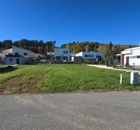 Plots - housing in Kováčová with family houses in the background and green grass.