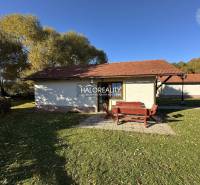 A cottage in Liptovský Mikuláš surrounded by an autumn garden and a pond with a wooden bridge.