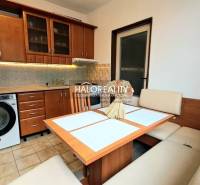 A kitchen in a studio apartment with a wooden decor and a corner sofa.