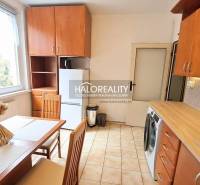 A kitchen in a studio apartment with ceramic tiles and a wooden decor kitchen unit.