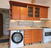 Kitchen unit with wood decor, washing machine and stove in a studio apartment.