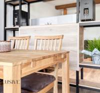 Dining table with chairs, a shelf, and a plant in a 3-room apartment with a wood-patterned floor.