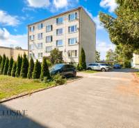 A view of the apartment building on Stummerova Street in Topoľčany surrounded by greenery and a parking lot.