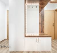 A hallway in a 3-room apartment with a wooden decor floor and a mirror.