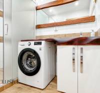 A bathroom with a washing machine, a sink, and a floor with a wooden decor in a 3-room apartment.