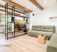 Living room in a three-room apartment with a wooden decor floor and green sofas.