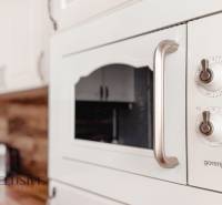 White Gorenje kitchen oven with control knobs, wooden decor on the wall in a 3-room apartment.