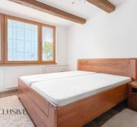 Bedroom with wooden beams, large wooden window, and a bed in a 3-room apartment.