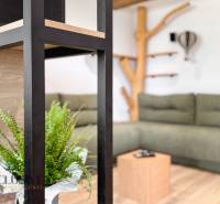 Design interior of a 3-room apartment with a comfortable sofa, wooden decor flooring, and decorations.