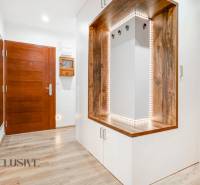 A hallway in a 3-room apartment with a wooden decor floor and built-in lighting.
