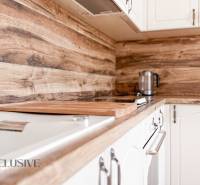 A kitchen in a 3-room apartment with white cabinets and wooden decor on the backsplash.