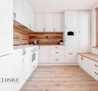 A kitchen in a 3-room apartment with white cabinetry and a floor with a wood decor.