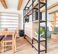 Dining table and sofa in a 3-room apartment with a wooden decor floor.