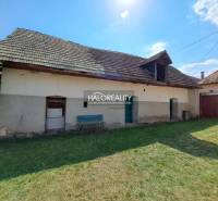 A family house in Zvolen with a wooden roof, a green yard, a bench, and a concrete facade.