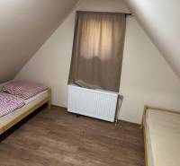 The attic of the cottage with two beds and a curtain.